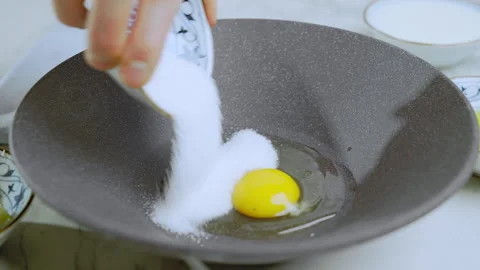A cook adds sugar to a raw egg to beat the egg to make a sweet dish. Stock Footage 269769719
