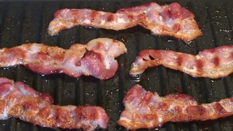Cook and prepares bacon strips for eating in closeup. 스톡 동영상 334641701