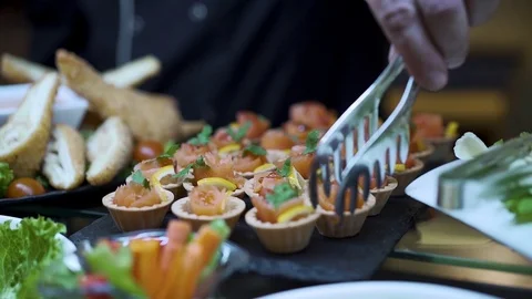 The cook arranges a table with snacks takes a basket of red fish Stock Footage 126544376