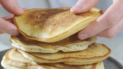 The cook arranges the thick American-style pancakes on a plate in a tower. Stock Footage 269769839