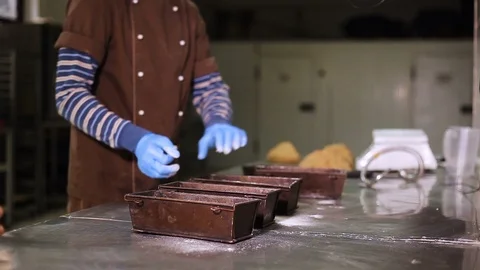 Cook at the bakery smears bakeware with flour Vidéo 106482819