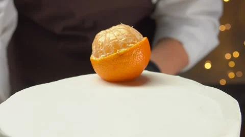 Cook in black gloves is decorating the cake with ctangerine persimmon Stock Footage 292679425