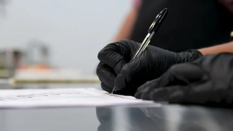 A cook in black gloves in the kitchen writes down a recipe with a black pen in a 스톡 동영상 283554245