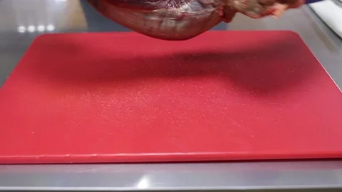 A cook in blue gloves puts the raw meat on a red chopping board and turns it ove Video stock 130903725