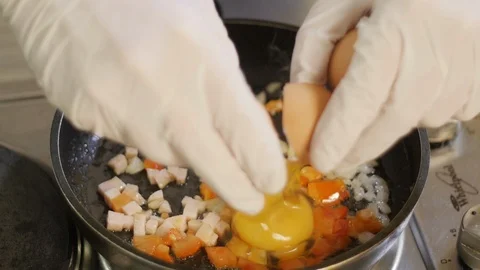 Cook Breaking Eggs in a frying Pan with Vegetables Stock Footage 98149147