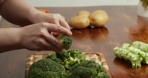 Cook Breaking fresh broccoli into florets on a wooden cutting board. Stock Footage 319388452