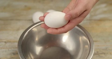 Cook breaks 3 raw eggs in a metal bowl Stock Footage 113422563