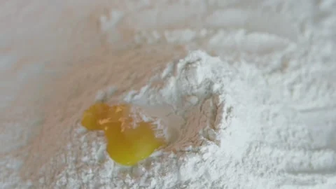 A cook breaks an egg and adds the yolk to wheat flour. Stock Footage 297947337