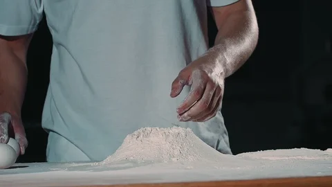 The cook breaks the egg into flour. Stock Footage 92578654