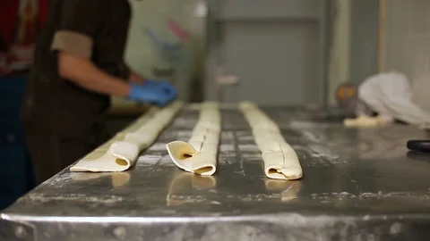 Cook in the brown uniform that makes the roll with a stuffing in the kitchen Stock Footage 106476973