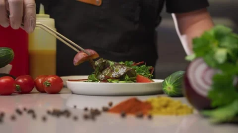 Cook carefully, using special tongs in the restaurant kitchen, adds tomatoes to Stock Footage 291723984