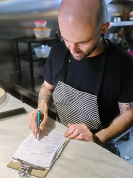 Cook checking the list of tasks to prepare the tasting menu in a restaurant Stock Photos