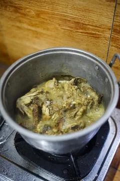 Cook chicken by boiling it using a pan Stock Photos