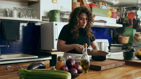 Cook chopping vegetables on a cutting board in a large kitchen with an array of Stock Footage 199455643