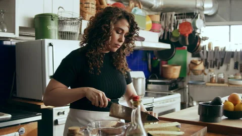 Cook chopping vegetables on a cutting board in a large kitchen with an array of Stock Footage 199455987