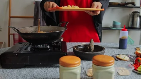 Cook chops fresh ingredients on cutting board scrapes them into hot wok and Stock Footage 342677685