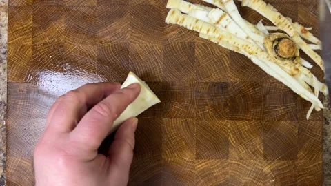 A cook chops parsley root with a knife on a wooden cutting board.	 Stock Footage 302277225