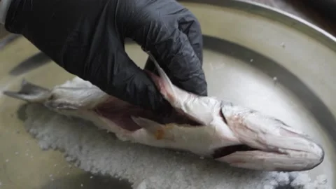 The cook cleans the baked fish from salt. Stock Footage 156525307