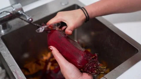 The cook cleans fresh beets with a special knife in an iron sink in the Video stock 196979733
