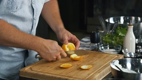 Cook cleans orange with sharp knife, peels it from orange peel, close-up shot Stock Footage 125730903