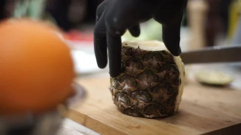 Cook cleans pineapple with a knife for making juice Stock-Footage 107077762