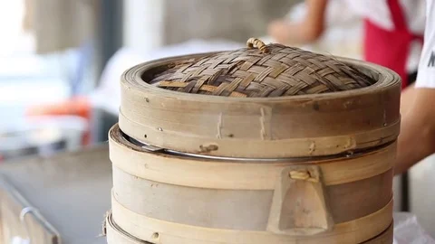 A cook is closing a bamboo steamer with dumplings inside for steam cooking. Stock Footage 74221271