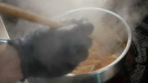 The cook is cooking dinner in the kitchen. Black gloves on hand Stock-Footage 127429972