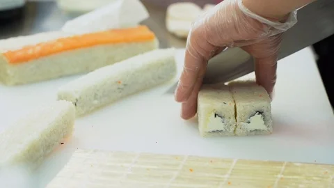 Cook cooking rolls. Man in transparent white gloves skillfully cuts sushi rolls. Stock Footage 119979014