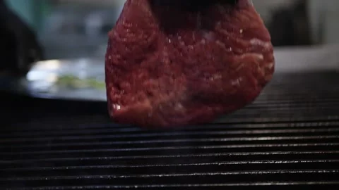 The cook cooks the meat in the kitchen a chop on the grill the stove Stock Footage 142035989