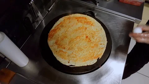 Cook cracking an egg on crepe on a black cooker Stock Footage 103872368