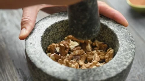 The cook crushing walnuts in a stone mortar. Stock Footage 237426947