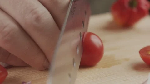 Cook cuts beautiful cherry tomatoes with sharp knife on wooden board Stock Footage 123207598