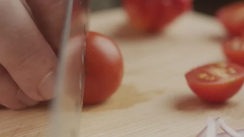 Cook cuts beautiful cherry tomatoes with steel knife on wooden board Stock Footage 123366442