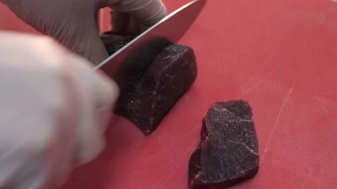 Cook cuts the beef into pieces with a large knife. Video stock 131333397