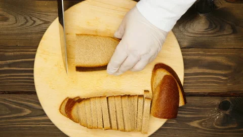 The cook cuts black bread with a large knife into small strips on a wooden Stock Footage 173471452