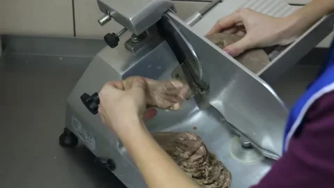 Cook cuts boiled beef meet with a slicer Stock Footage 143782113