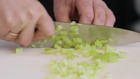The cook cuts celery stalks with a large kitchen knife into small slices. Stock Footage 302646193
