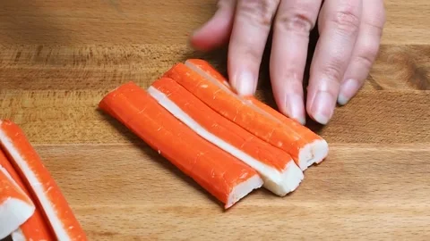 The cook cuts crab sticks on a cutting board into slices. closeup. 動画素材 346800629