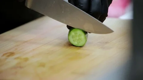 The cook cuts the cucumber with a sharp knife on a cutting board Stock Footage 127202280