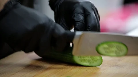 The cook cuts the cucumber with a sharp knife on a cutting board Stock Footage 127202465
