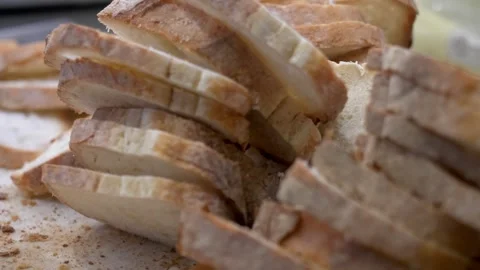 Cook cuts fresh bread into even slices for bruschetta Stock Footage 336793357