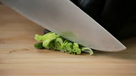 The cook cuts green onions with a sharp knife on a cutting board Stock Footage 127204687