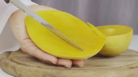 A cook cuts a juicy ripe mango. Close-up Video stock 123686491
