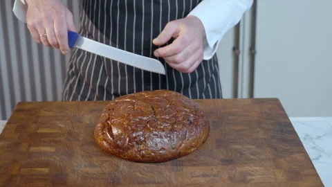 The cook cuts the loaf of bread in half with a large bread knife. Stock Footage 275250174