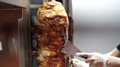 A cook cuts meat to make shawarma, gyros, doner kebab. Stock Footage 142875763