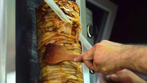 A cook cuts meat to make shawarma, gyros, doner kebab. Cooking meat on a skewer Vidéo 162187624