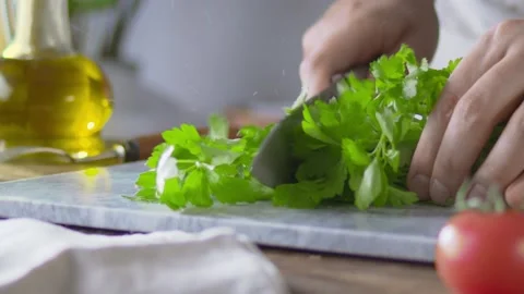 Cook cuts Parsley with large kitchen knife on marble kitchen cutting board Video stock 144676356