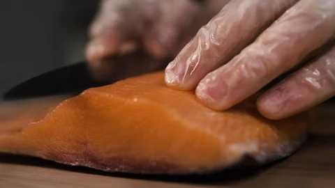 The cook cuts a piece of red fish with a knife Stock Footage 124211181