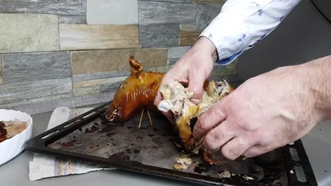The cook cuts into pieces a pig baked in the oven. portioned distribution of a Stock Footage 205212967