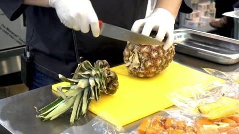 The cook cuts pineapple in the kitchen. 库存影片 92369966